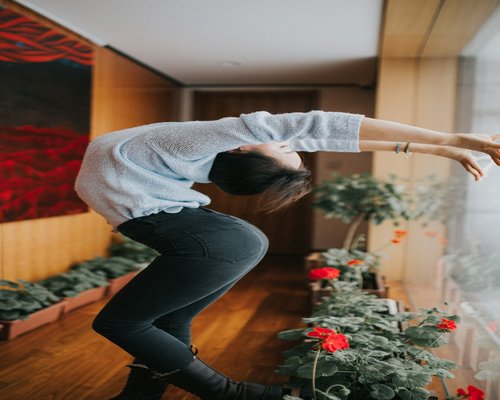 An office worker softly stretching their arms and neck at home near a plant with soft natural illumination